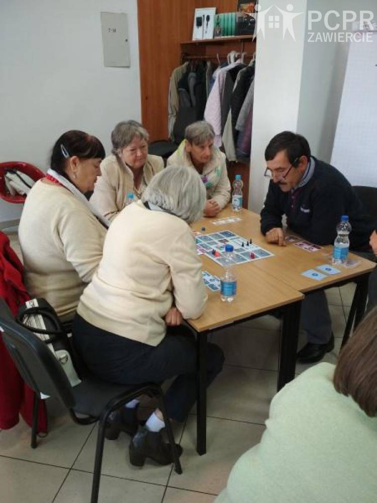 Zdjęcie: Kobiety i mężczyźni siedzą przy stole na którym leży gra planszowa
